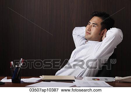 Stock Photo - man relaxing at work with hands behind his head. Fotosearch