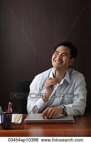 Man sitting at desk smiling View Large Photo Image Stock Photo - Man sitting at desk smiling. Fotosearch