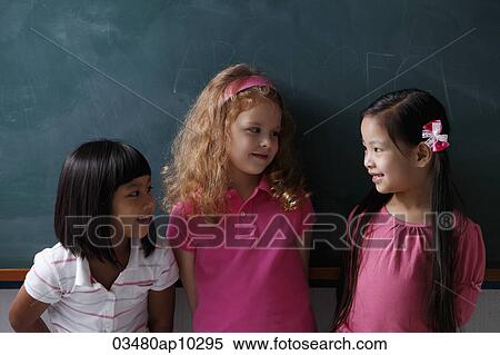 Stock Photography - three young girls smiling at each other. Fotosearch