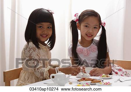 Picture - two little girls having a tea pary. Fotosearch