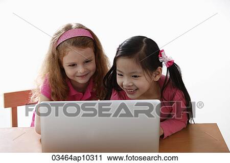 Stock Image - two young girls looking at laptop. Fotosearch