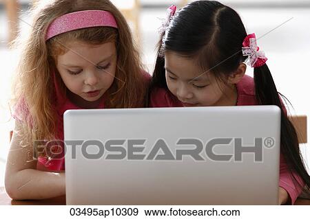 Two young girls looking at laptop View Large Photo Image Stock Photo - Two young girls looking at laptop. Fotosearch