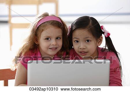two young girls playing with laptop View Large Photo Image Stock Image - two young girls playing with laptop. Fotosearch