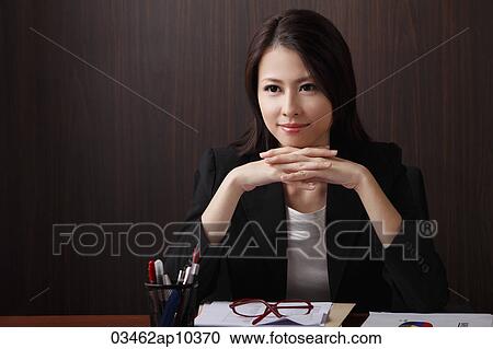 Woman sitting at desk with hands folded View Large Photo Image Stock Image - Woman sitting at desk with hands folded. Fotosearch