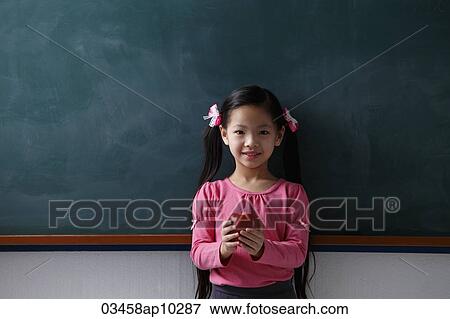 Young girl holding a red apple in front of chalk board View Large Photo Image Stock Photo - Young girl holding a red apple in front of chalk board. Fotosearch