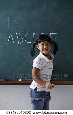 Young girl smiling in front of chalk board View Large Photo Image Stock Image - Young girl smiling in front of chalk board. Fotosearch