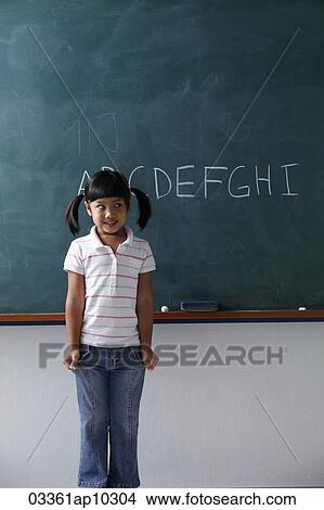 young girl standing in front of the chalkboard smiling View Large Photo Image Picture - young girl standing in front of the chalkboard smiling. Fotosearch
