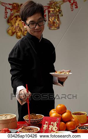Young man getting food at Chinese New Year party View Large Photo Image Stock Photograph - Young man getting food at Chinese New Year party. Fotosearch