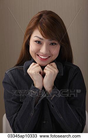 Young woman smiling with hands under chin View Large Photo Image Stock Image - Young woman smiling with hands under chin. Fotosearch