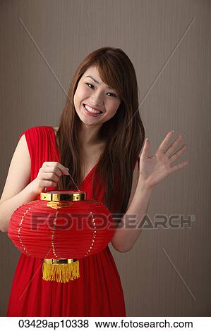 Young woman wearing red dress, holding red lantern and waving View Large Photo Image Stock Photo - Young woman wearing red dress, holding red lantern and waving. Fotosearch