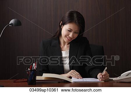 Young woman writing at her desk View Large Photo Image Stock Image - Young woman writing at her desk. Fotosearch