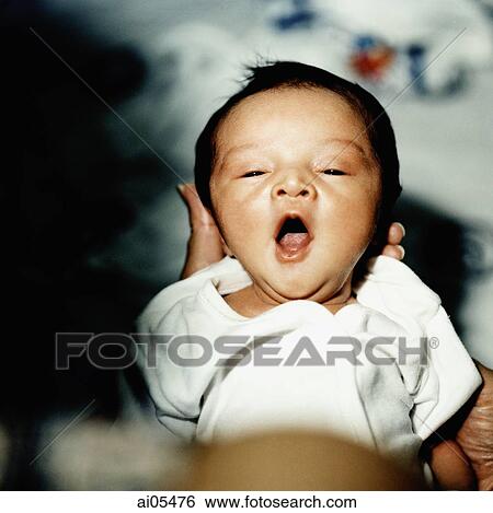 Stock Photograph - Baby yawning while being held. Fotosearch