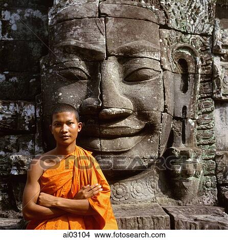 Cambodia, Ankor Thom, portrait of monk in front of the face of Avalokitesvara View Large Photo Image Picture - Cambodia, Ankor Thom, portrait of monk in front of the face of Avalokitesvara. Fotosearch