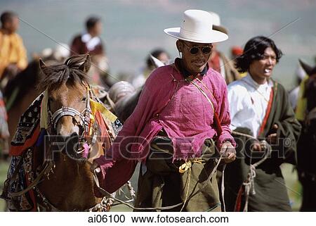 Stock Image - China, Szechuan (Sichuan), Kham region, Nomad man in traditional silk shirt leading horse at summer festival.. Fotosearch
