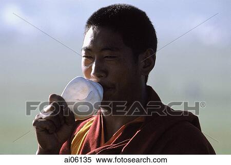 Stock Photography - China, Szechuan (Sichuan), Kham region, Tibetan monk blowing on conch shell as a prayer call during the summer nomad festival.. Fotosearch