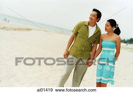 Stock Photo - Couple at beach holding hands ( high grain). Fotosearch