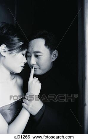 Couple embracing, woman with finger to mans lips View Large Photo Image Stock Photograph - Couple embracing, woman with finger to mans lips. Fotosearch