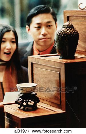 Couple looking in antique store window, Buddha statue in foreground View Large Photo Image Stock Photo - Couple looking in antique store window, Buddha statue in foreground. Fotosearch