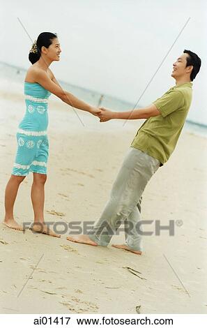 Stock Photo - Couple on beach holding hands ( high grain). Fotosearch