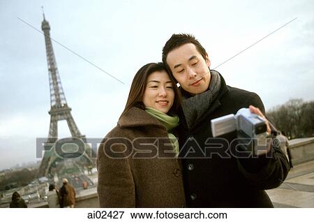 Couple videotaping themselves in front of Eiffel Tower. View Large Photo Image Stock Photo - Couple videotaping themselves in front of Eiffel Tower.. Fotosearch
