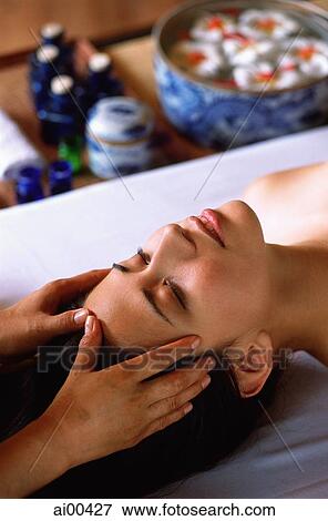 Stock Photo - Eurasian female lying down receiving a head massage. Fotosearch