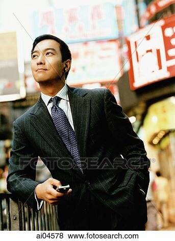 Stock Photo - Executive holding cellular phone on street looking off camera.. Fotosearch
