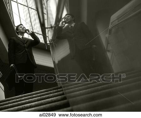 Executive using cellular phone on top of stairs, building in background, reflection on stairwell. View Large Photo Image Stock Photo - Executive using cellular phone on top of stairs, building in background, reflection on stairwell.. Fotosearch