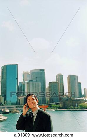 Executive using cellular phone, skyline in background View Large Photo Image Stock Photo - Executive using cellular phone, skyline in background. Fotosearch