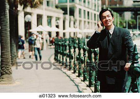 Stock Image - Executive using cellular phone, walkway in background. Fotosearch