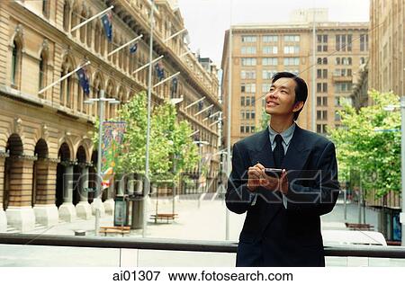 Executive using PDA, buildings in background View Large Photo Image Stock Photo - Executive using PDA, buildings in background. Fotosearch