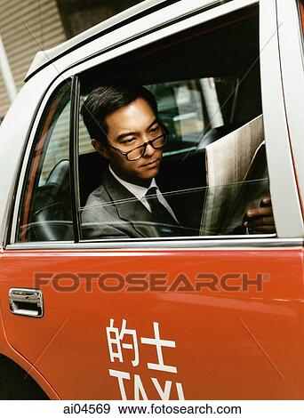 Executive wearing glasses reading newspaper in taxi. View Large Photo Image Stock Photo - Executive wearing glasses reading newspaper in taxi.. Fotosearch