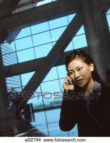 Executive woman using cellular phone indoors, windows in background. View Large Photo Image Picture - Executive woman using cellular phone indoors, windows in background.. Fotosearch
