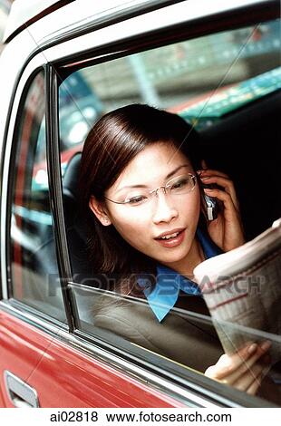 Executive woman using cellular phone and reading newspaper in taxi. View Large Photo Image Stock Photo - Executive woman using cellular phone and reading newspaper in taxi.. Fotosearch