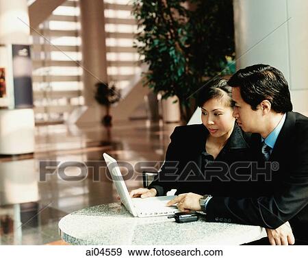 Executives sitting at table looking at laptop. View Large Photo Image Stock Photo - Executives sitting at table looking at laptop.. Fotosearch