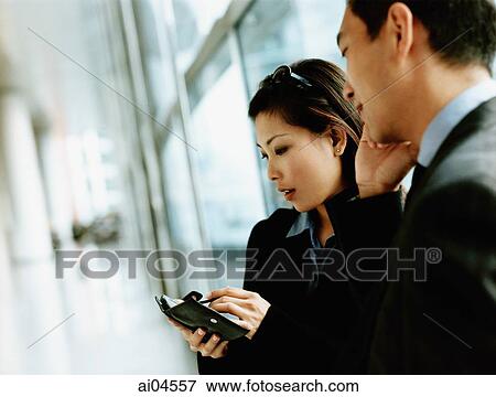 Stock Photo - Executives using PDA and cellular phone.. Fotosearch