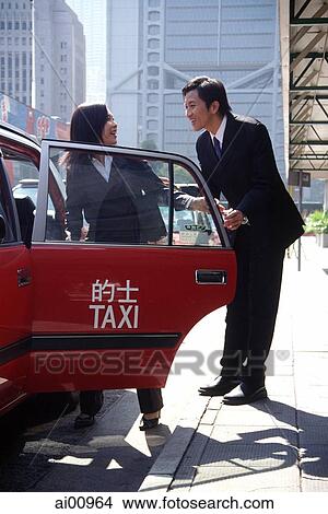 Picture - Female executive getting into taxi, male executive holding door. Fotosearch