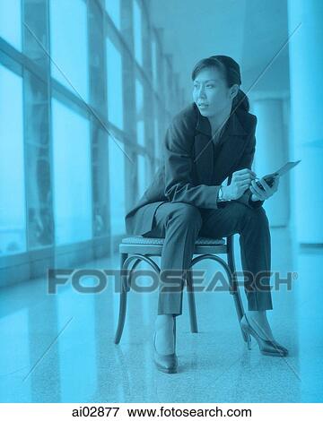 Female executive holding PDA sitting by window. View Large Photo Image Stock Photo - Female executive holding PDA sitting by window.. Fotosearch