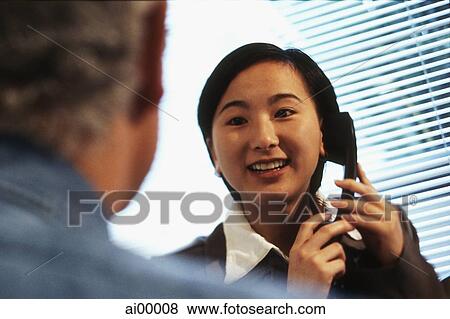 Female executive holding telephone talking with Caucasian male executive View Large Photo Image Stock Photo - Female executive holding telephone talking with Caucasian male executive. Fotosearch