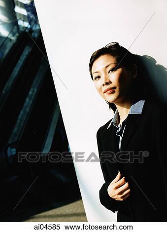 Stock Photography - Female executive leaning against wall, portrait.. Fotosearch