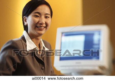 Female executive sitting at desk with computer, portrait, yellow background View Large Photo Image Picture - Female executive sitting at desk with computer, portrait, yellow background. Fotosearch