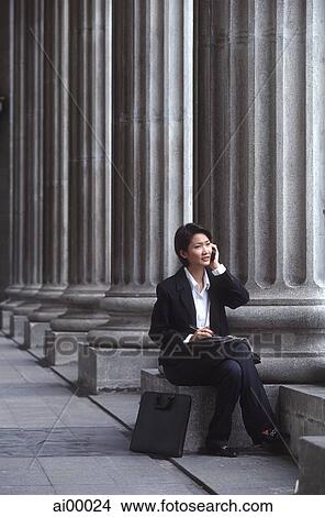 Female executive sitting, using cellular phone View Large Photo Image Picture - Female executive sitting, using cellular phone. Fotosearch