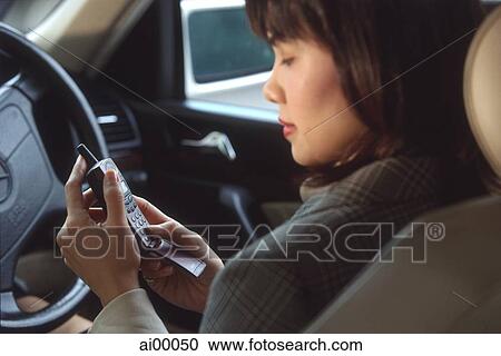 Stock Image - Female executive using cellular phone in car, profile. Fotosearch
