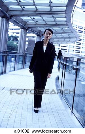 Female executive walking along aisle of building View Large Photo Image Stock Image - Female executive walking along aisle of building. Fotosearch