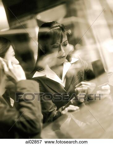 Female executives using PDA and cellular phone seen through glass window. View Large Photo Image Stock Photo - Female executives using PDA and cellular phone seen through glass window.. Fotosearch