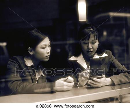 Female executives using PDA and cellular phone seen through glass window. View Large Photo Image Stock Photo - Female executives using PDA and cellular phone seen through glass window.. Fotosearch