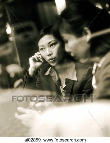 Female executives using PDA and cellular phone seen through glass window. View Large Photo Image Stock Photo - Female executives using PDA and cellular phone seen through glass window.. Fotosearch