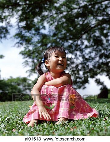 Girl sitting on grass laughing, tree in background View Large Photo Image Stock Photo - Girl sitting on grass laughing, tree in background. Fotosearch