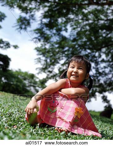 Girl sitting on grass, tree in background View Large Photo Image Stock Photo - Girl sitting on grass, tree in background. Fotosearch