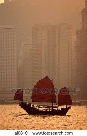 Stock Image - Hong Kong, Junk in harbor, buildings in background.. Fotosearch