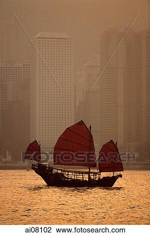 Stock Image - Hong Kong, Junk in harbor, buildings in background.. Fotosearch
